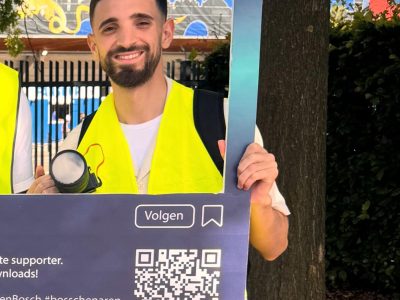 Teamlid van Fellow Productions met promotiebord in de stad